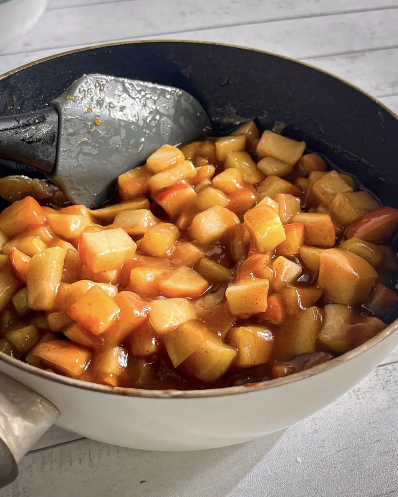 Cinnamon-spiced apple pie filling cooking in a saucepan